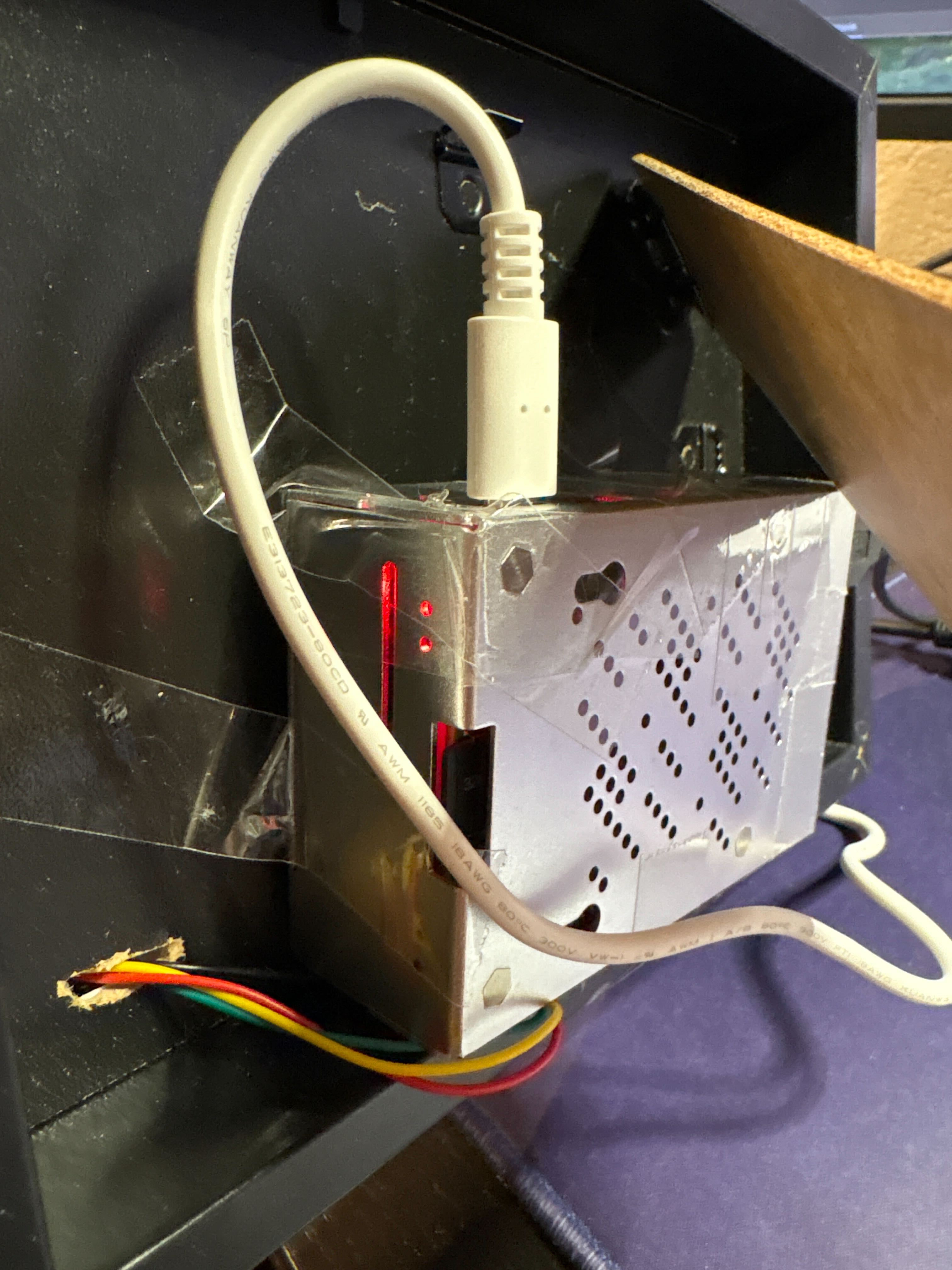 Foto av baksiden av rammen der raspberry pi holdes på plass med teip